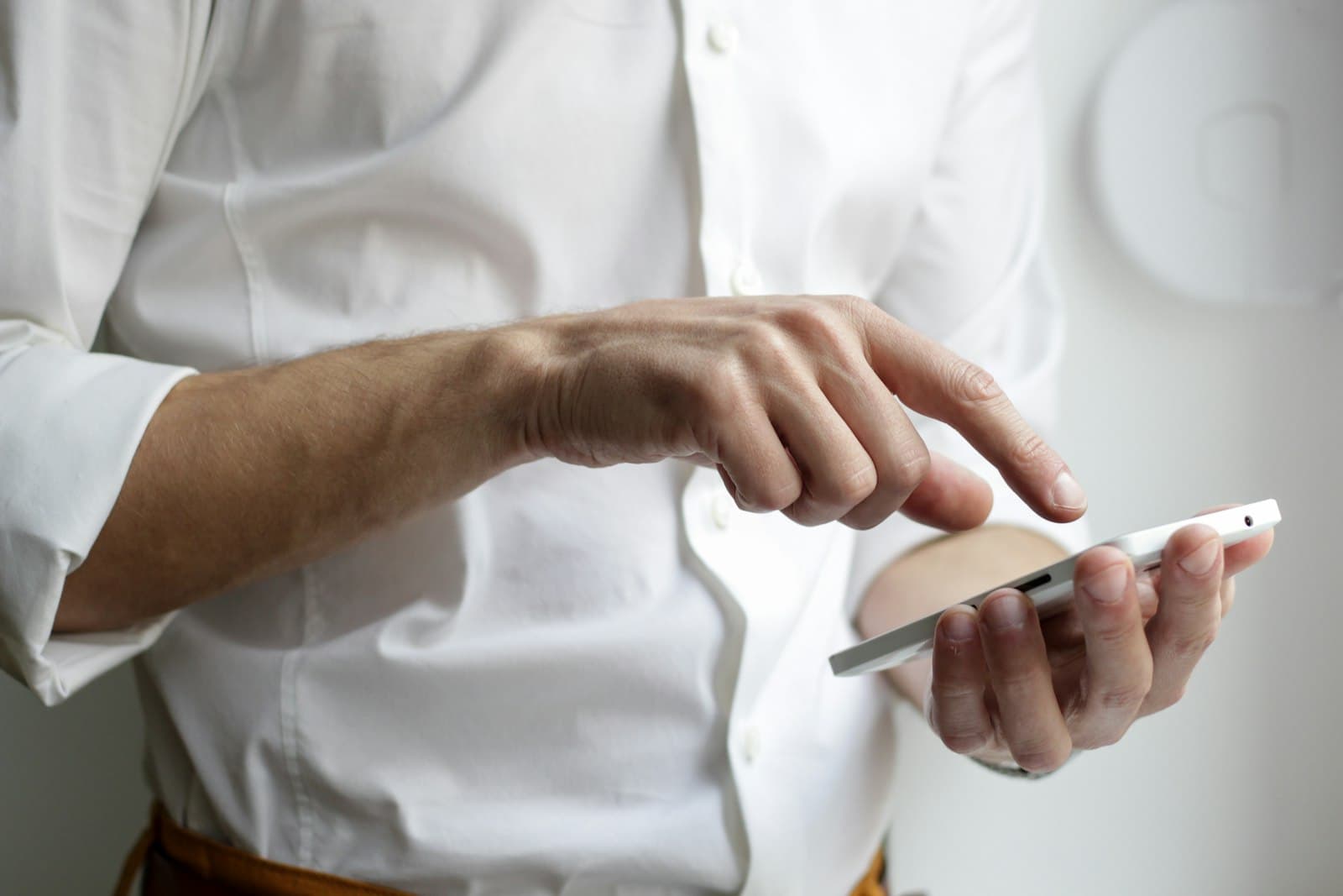 A person in business attire holding a smartphone — the legitimate phone-automation use case the post describes.